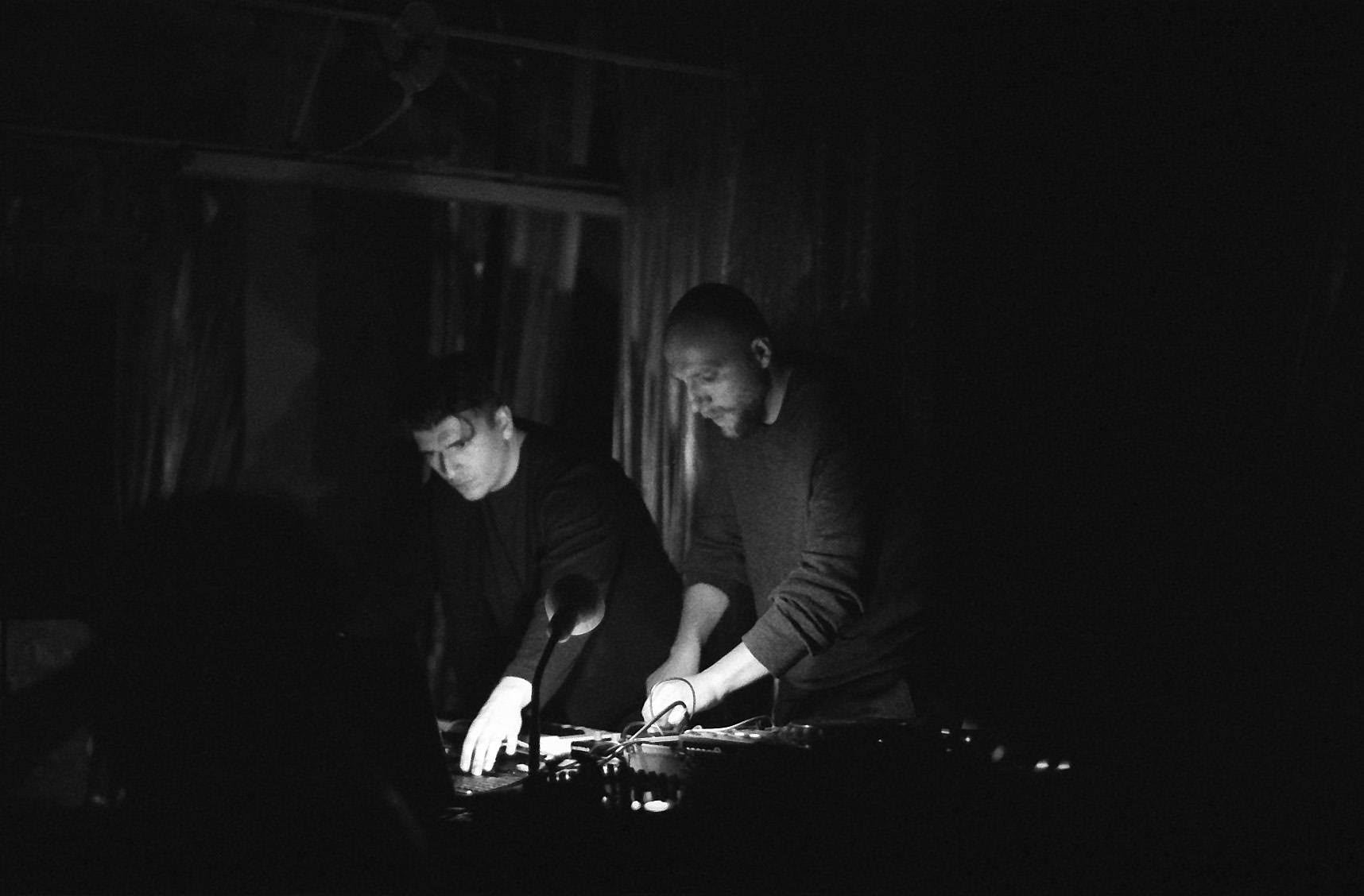 Dual Shaman performing in near darkness, black and white